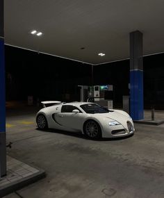 a white bugatti parked in a parking lot next to a blue gas pump