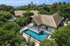 an aerial view of a house with a pool in the foreground and trees surrounding it