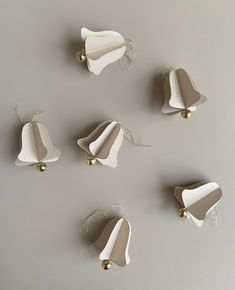 five pieces of paper with bells attached to them on a gray surface, all in different shapes and sizes