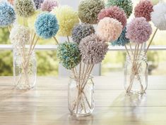 several vases filled with different colored pom - poms on top of a wooden table