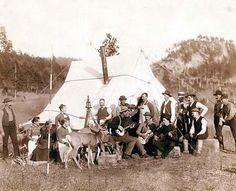 a group of people standing next to each other in front of a teepee tent