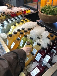 bottles of juice are lined up on a table with ice and flowers in the background