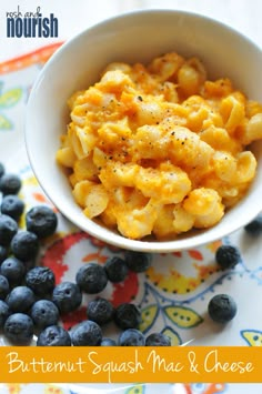 a white bowl filled with macaroni and cheese next to blueberries