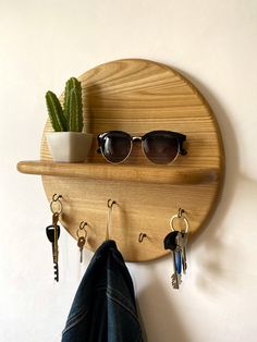 a pair of sunglasses hanging on a wooden shelf with key hooks and a potted cactus