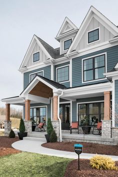 a large blue and white house with lots of windows on it's front porch