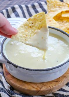 a hand dipping a tortilla chip into a bowl of quesadilla dip