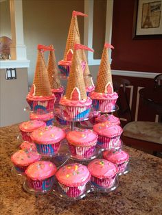 cupcakes are stacked on top of each other in pink frosting and cones