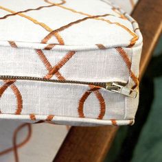 a close up of a white and orange cushion on a chair with a metal zipper