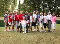 a group of older people standing next to each other in front of a body of water