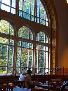 a person sitting at a desk in front of a large window with lots of windows