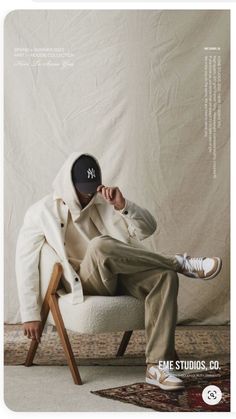 a man sitting on top of a white chair holding a black object over his face