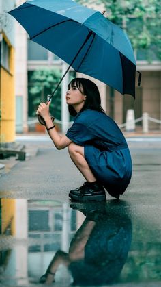 a woman kneeling on the ground holding an umbrella