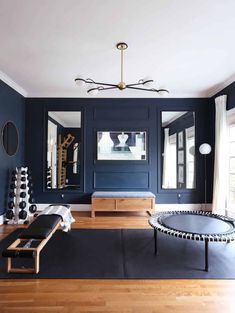 a living room with blue walls and wooden floors, black furniture and mirrors on the wall