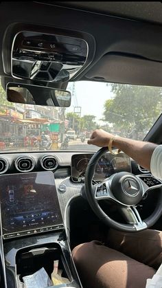 a man driving a car while holding a cell phone in his hand and steering wheel