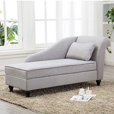 a gray chaise lounger sitting on top of a rug in front of a window