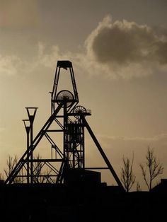 the silhouette of a roller coaster against a cloudy sky