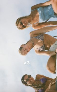 three women in bathing suits standing next to each other with the sky in the background