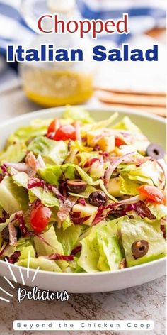 a salad with lettuce, tomatoes and olives is shown in a white bowl