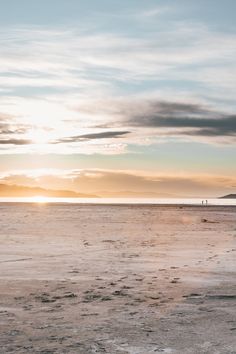 two people walking on the beach at sunset