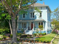 a blue two story house with trees and flowers in the front yard