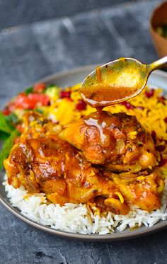 a spoon is being used to scoop some food out of a plate with rice and vegetables