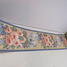 a floral border hanging from the ceiling in a room with white walls and blue trim