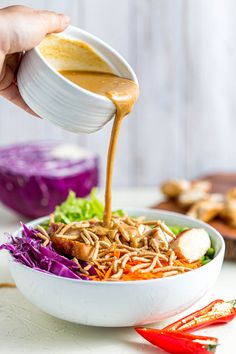 someone pouring dressing into a bowl of salad