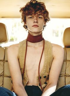 a young man sitting in the back seat of a car with his hands on his hips