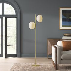 a living room with a couch, chair and two lamps on the floor in front of an arched window