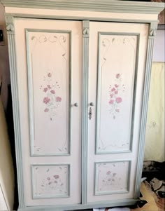 a white armoire with pink flowers painted on it