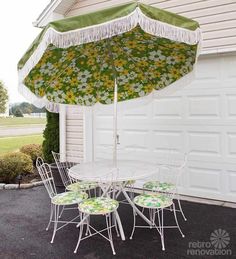 an umbrella and chairs are outside in front of a garage