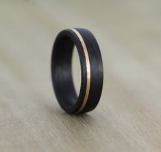 a black and gold wedding ring on top of a wooden table