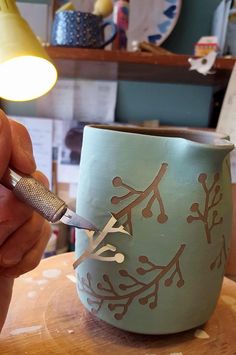 a person is using a sharp knife to decorate a cup