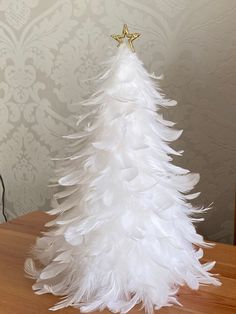 a white feather christmas tree sitting on top of a wooden table