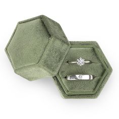 an open ring box with two rings in it and a diamond on the top one