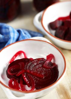 two bowls filled with beets on top of a wooden table