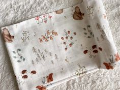 a table cloth with flowers on it laying on top of a white bed coverlet