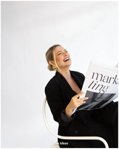 a woman sitting in a chair and holding a book with the title mark lines written on it