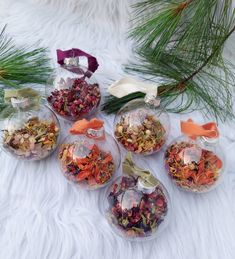 five clear glass containers filled with different types of dried flowers and herbs on a white furnishing