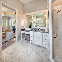 a large bathroom with marble floors and white cabinets, along with a walk in shower