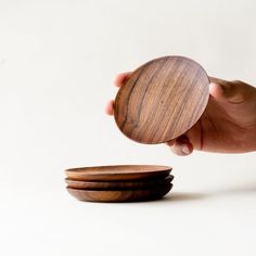 a hand holding a wooden bowl over three plates