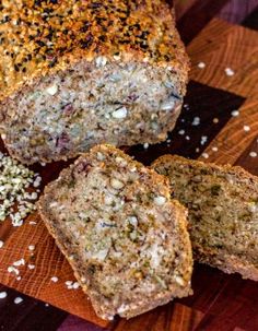 sliced loaf of bread sitting on top of a wooden cutting board with seeds and sprinkles