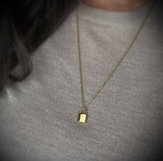 a woman wearing a gold necklace with a padlock on the front and back of her neck