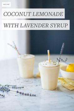 coconut lemonade with lavender syrup in two cups on a marble countertop next to dried lavenders