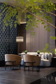 a living room filled with furniture next to a tall wooden wall covered in black and white tiles