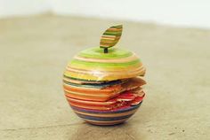 an apple made out of multicolored wooden slices on top of each other with a green leaf sticking out of it