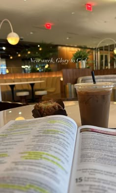 an open book sitting on top of a table next to a cup of coffee