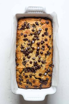 a loaf of chocolate chip bread in a white baking dish on a white counter top