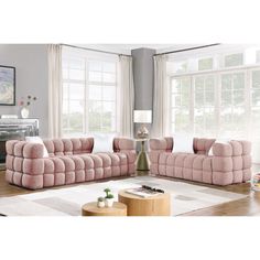 a living room filled with pink couches next to a white coffee table and windows