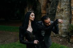 a man and woman dressed in black are posing for a photo together on the grass